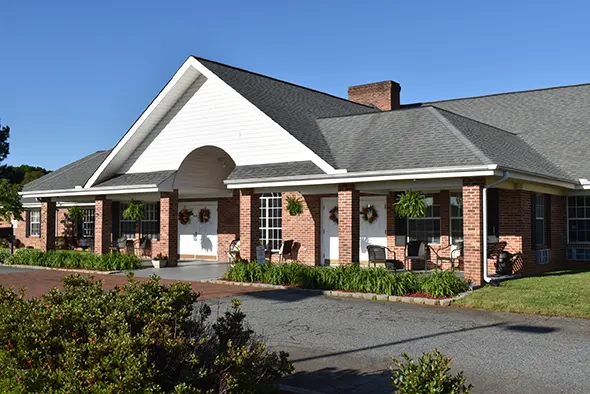 Front entrance of Caremoor Assisted Living with brick exterior, white trim, and welcoming seating.