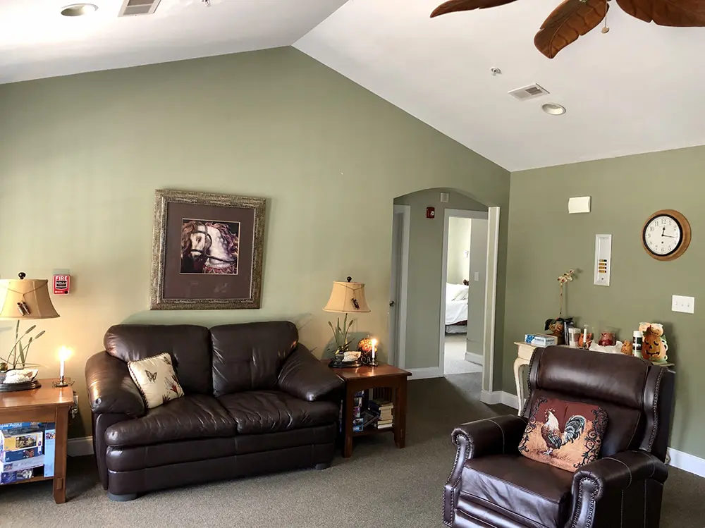 Cozy living area in The Carriage House with brown leather furniture, decorative artwork, and soft lighting.