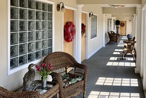 decorative indoor hallway at lamoor commons with wicker chairs, seasonal door wreaths, and glass block windows