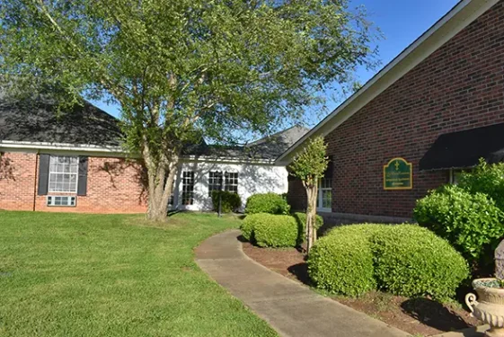Brick building with landscaped walkway and greenery at LaMoor Commons Independent Apartments.